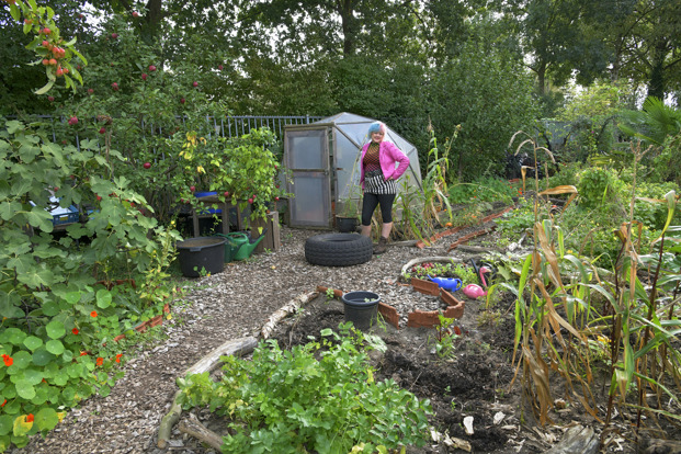 Vrouw met blauwroze haar en roze jasje in haar weelderige paradijstuin in Breda