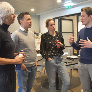 Twee vrouwelijke en een mannelijke medewerker luisteren naar andere mannelijke medewerker tijdens sessie gebiedsplannen